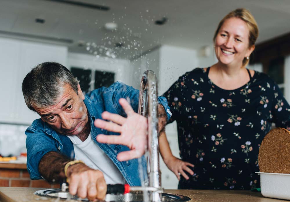 Clueless-looking person attempting DIY repairs on faulty pipes