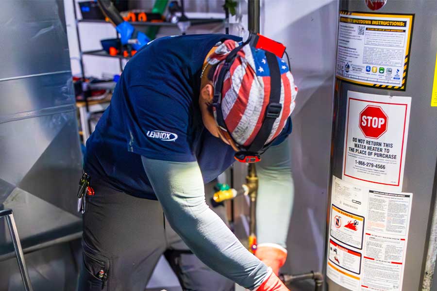 HVAC technician servicing a water heater in a utility room