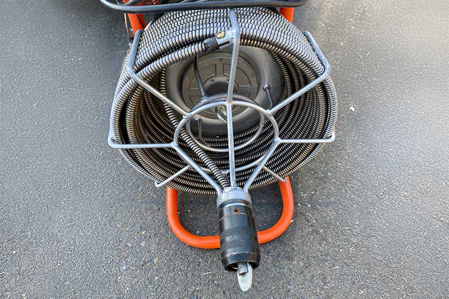 Close-up of a coiled drain snake with a cutting head.