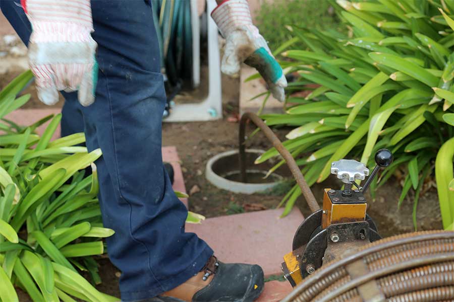 Plumber using a drain snake to clear a sewer line.