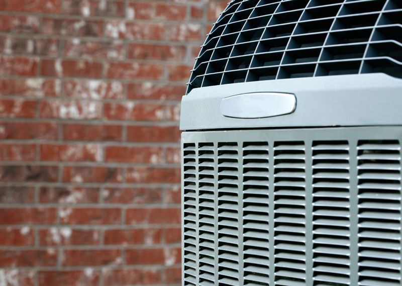 Close-up of an outdoor air conditioning unit with a brick wall background