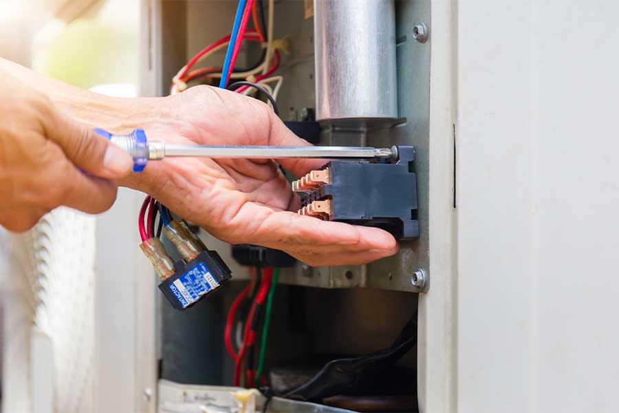 Technician using a screwdriver to repair an HVAC system component