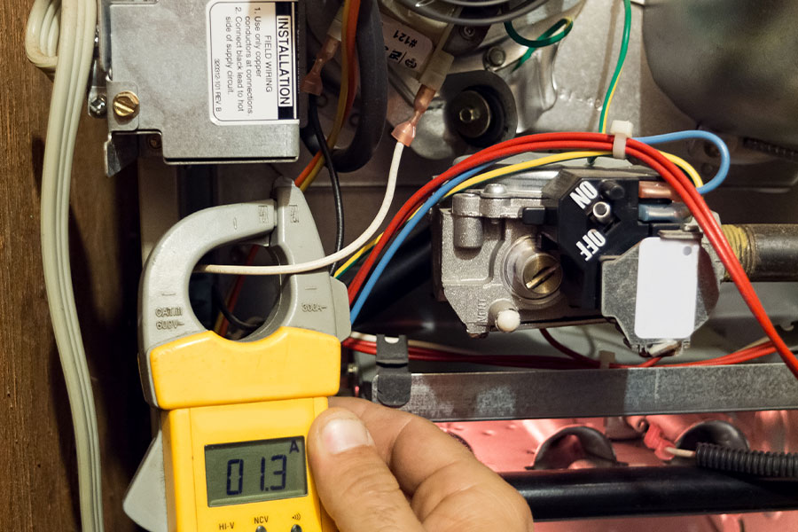 Technician using a clamp meter to measure current in an HVAC system