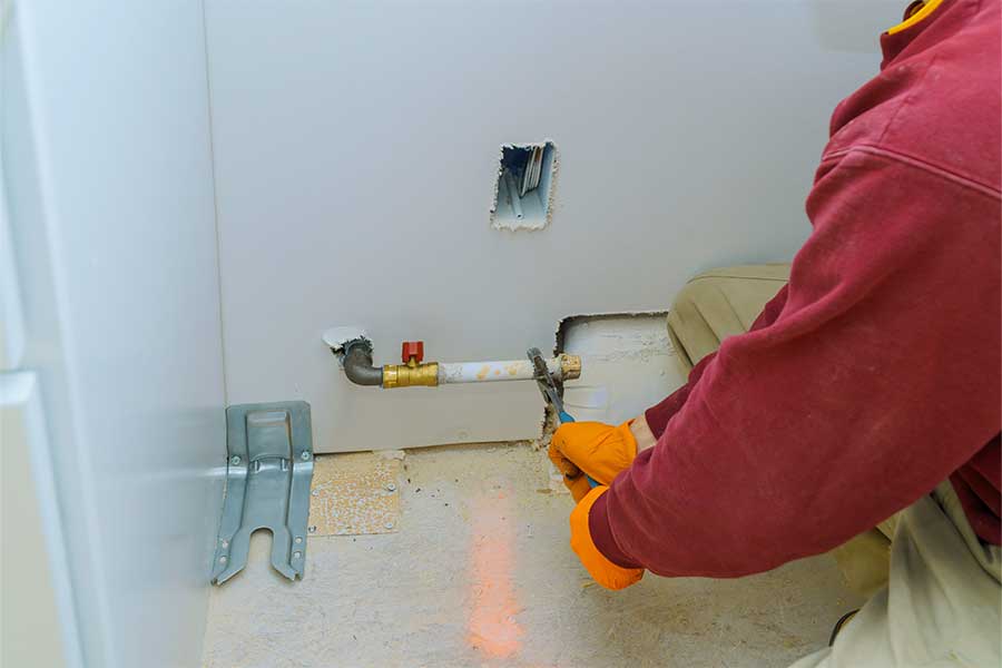 Worker repairing a gas line connection near a wall