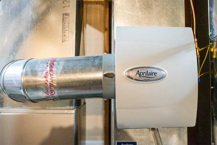 White Aprilaire humidifier unit connected to metal air ducts