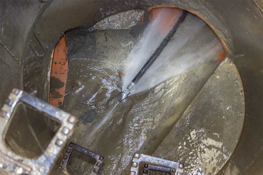 High-pressure water jet cleaning a sewer pipe