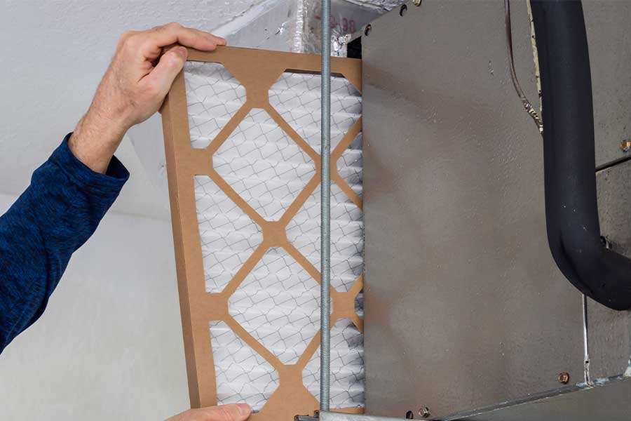 Person installing a new air filter in an HVAC system