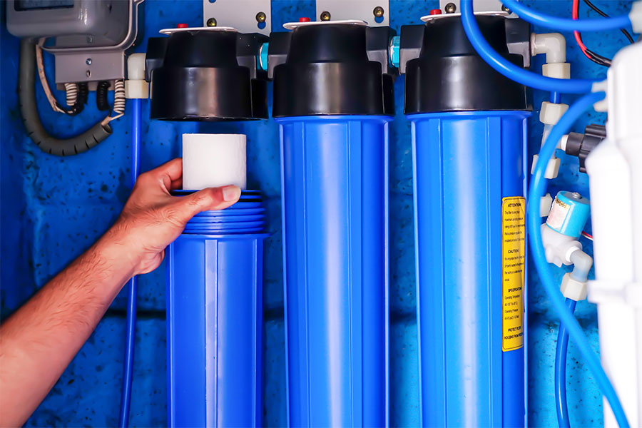 Person replacing a water filter cartridge in a blue filtration system.