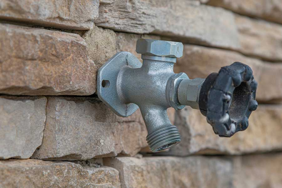 Outdoor water spigot mounted on a stone wall