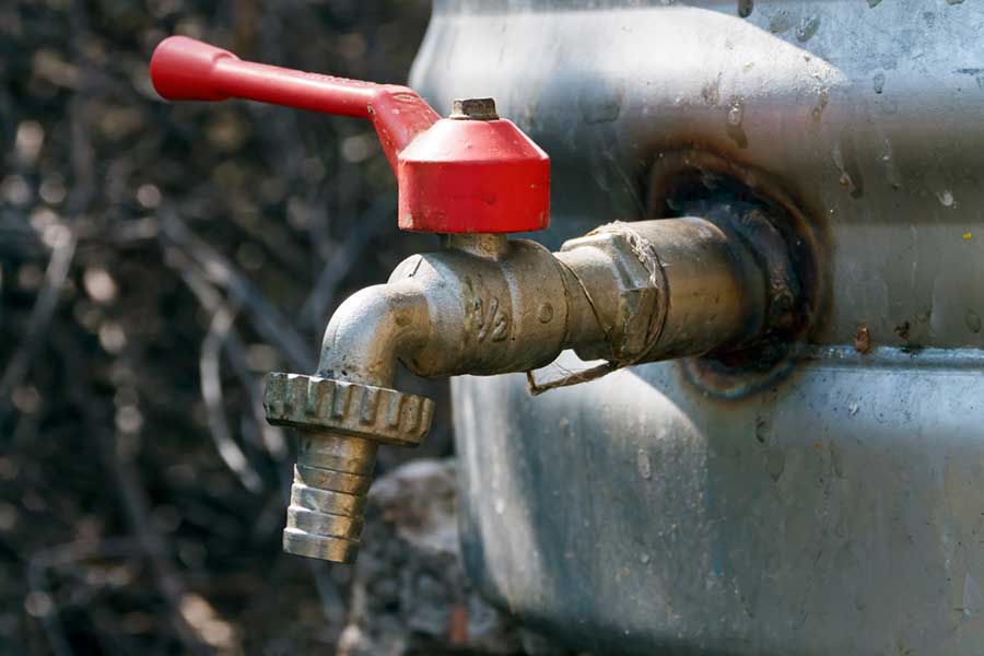 Rusty water tap mounted on a metal container