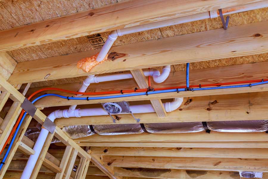 Exposed wooden ceiling framing with plumbing and electrical installations.