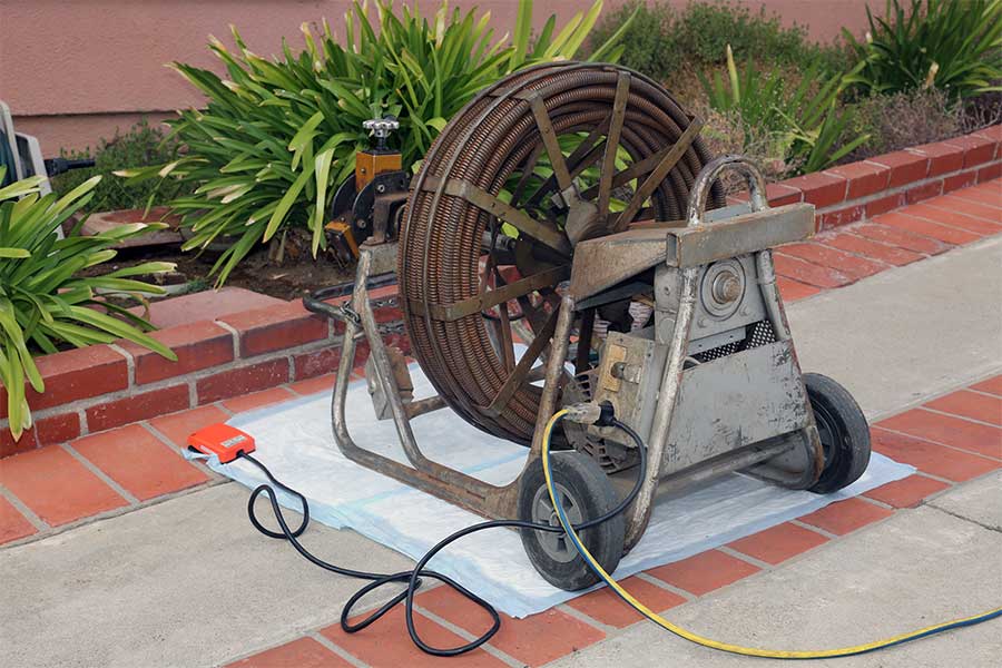 Heavy-duty sewer drain cleaning machine with a coiled cable on wheels