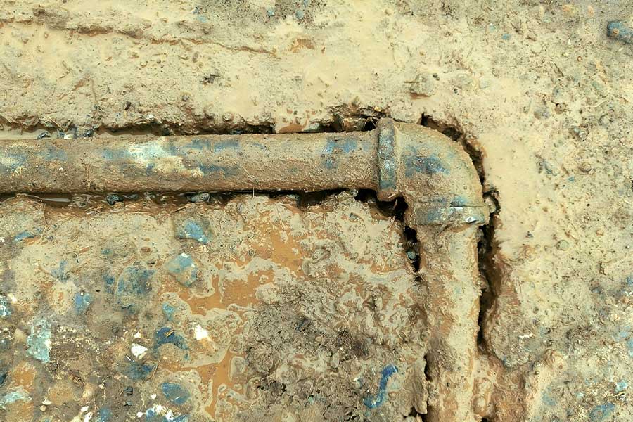 Old underground metal pipe covered in mud and corrosion