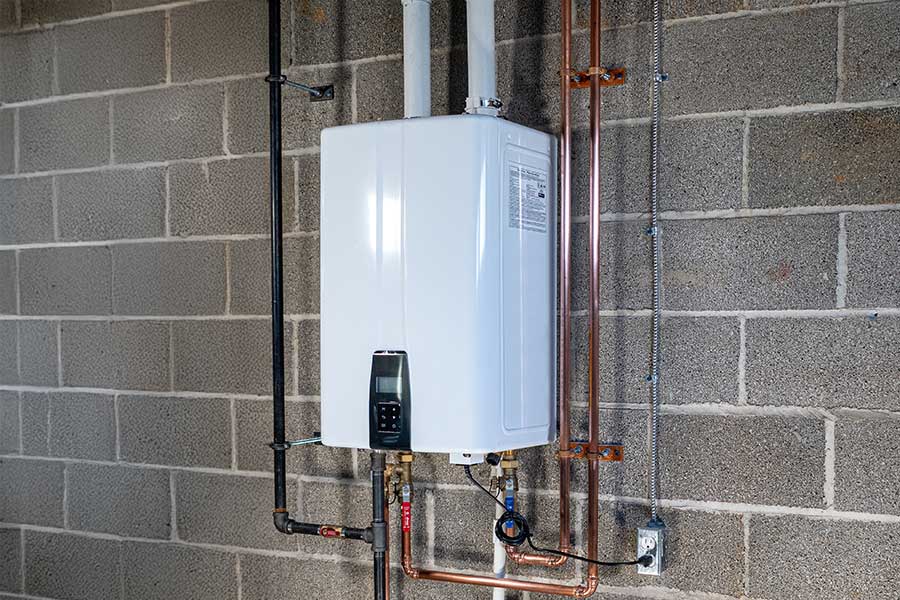 Wall-mounted tankless water heater installed on a concrete block wall