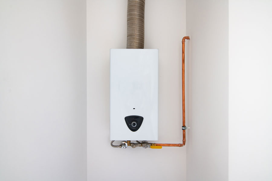 Compact gas water heater installed on a white wall with ventilation