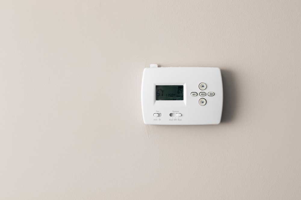 A thermostat installed on a smooth, neutral-colored wall