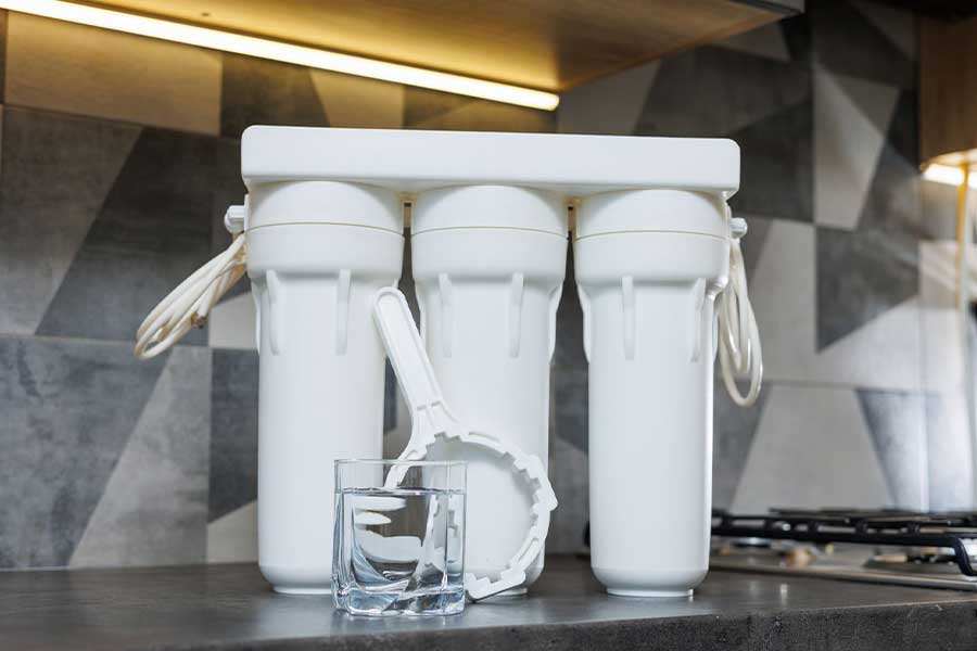 Water purifier with three filters and a glass of clean water