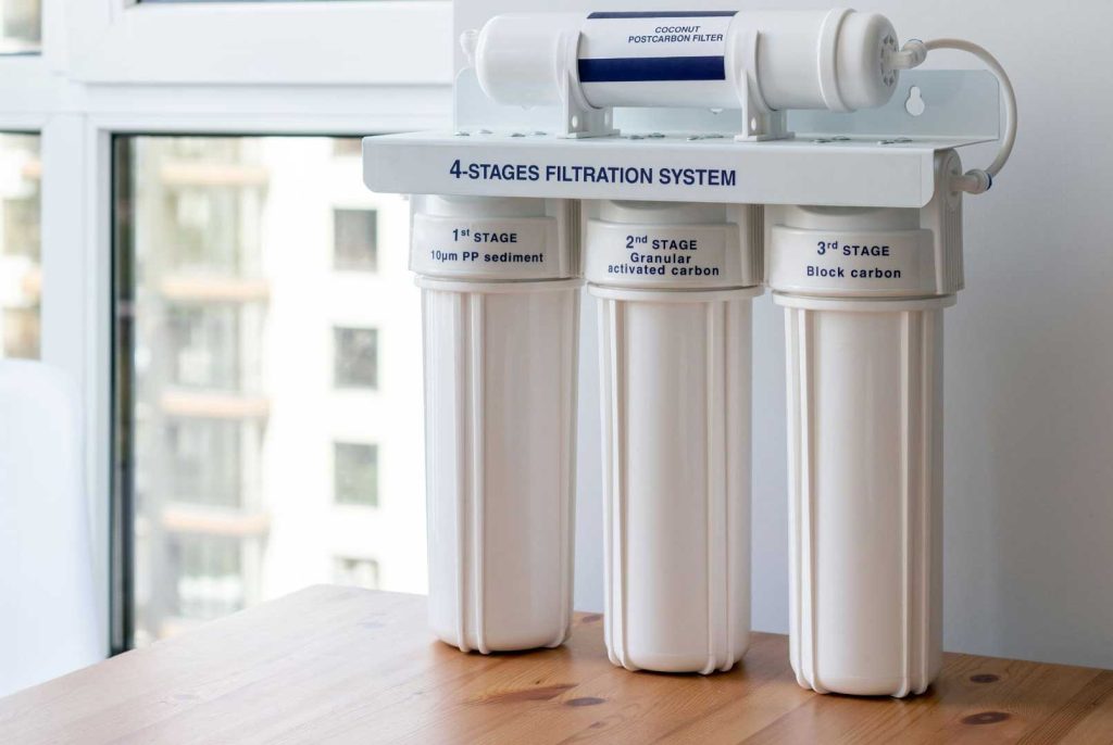 Four-stage water filtration system on a wooden table