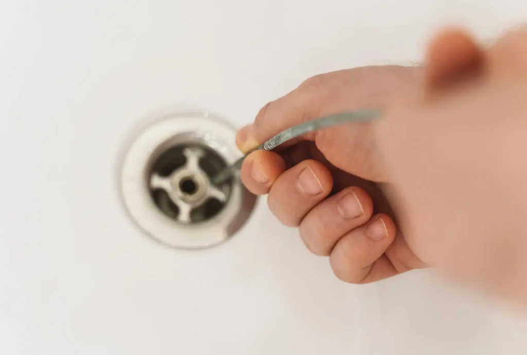 Hand using snake in drain