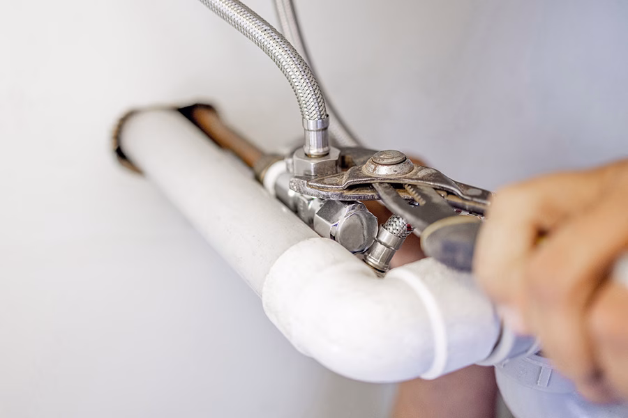 Plumber using wrench on water line