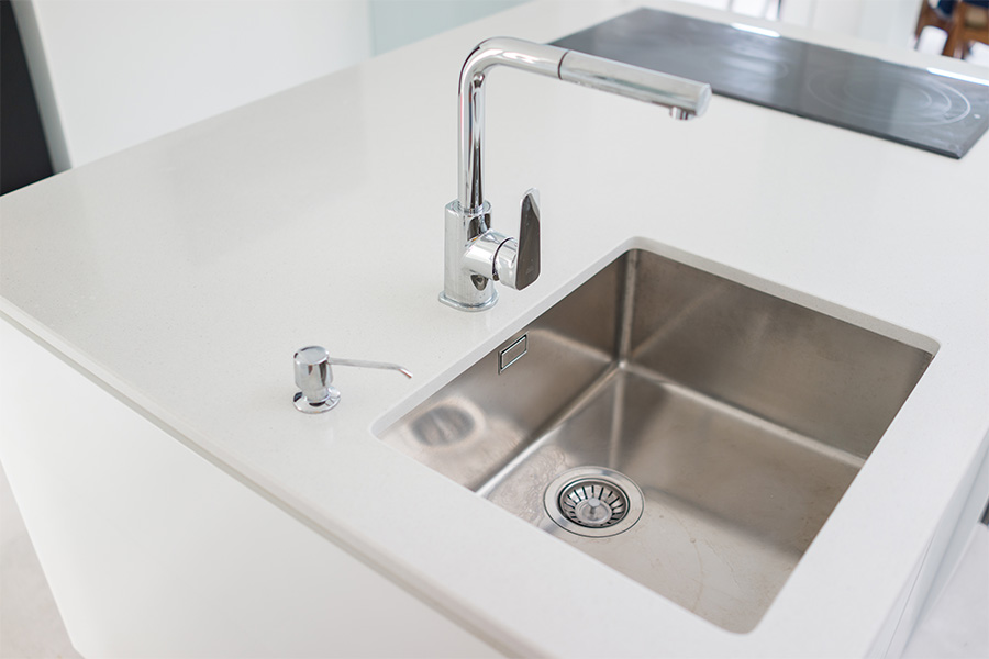 Stainless steel kitchen sink installation with chrome faucet and soap dispenser