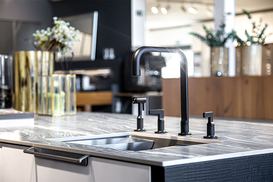 Modern kitchen sink and faucet installation with black fixtures and marble countertop